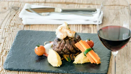 Gourmetgerecht met biefstuk, groenten, aardappelpuree en rode wijn op houten tafel