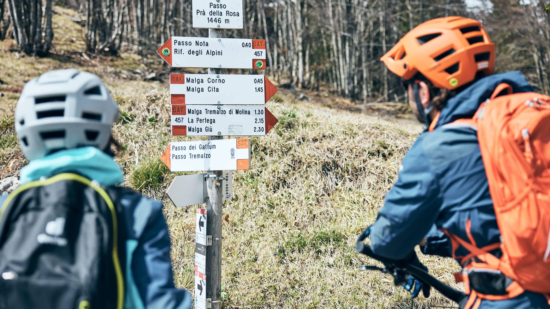 Zwei Fahrradfahrer vor einem Wegweiser im Gebirge bei Passo Prà della Rosa