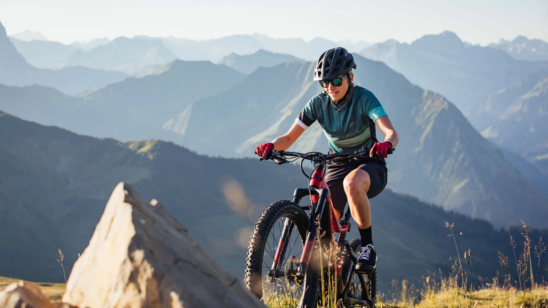 Mountainbike Urlaub für Anfänger
© Bregenzerwald Tourismus - Sebastian Stiphout Frau mountainbiket im Gebirge bei sonnigem Wetter mit Helm und Sonnenbrille