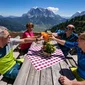 Four people toast with drinks on a mountain terrace with alpine view