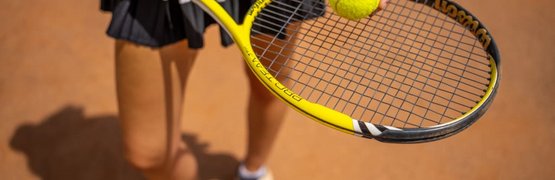 Short Game am Brennsee Frau hält einen Tennisball und Tennisschläger auf Sandplatz