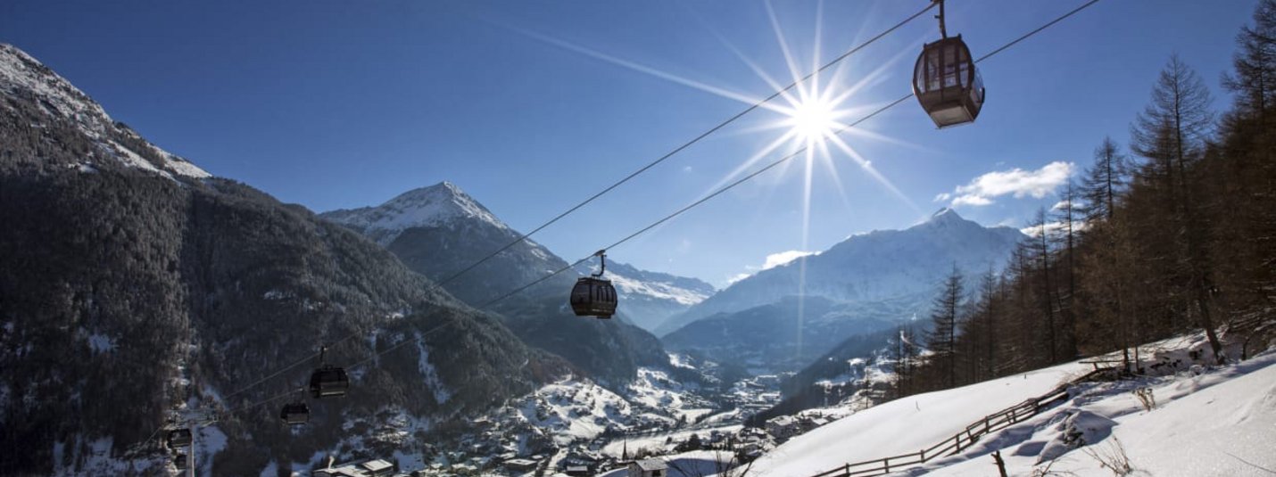 Cable car over snowy mountains and village on a sunny winter day