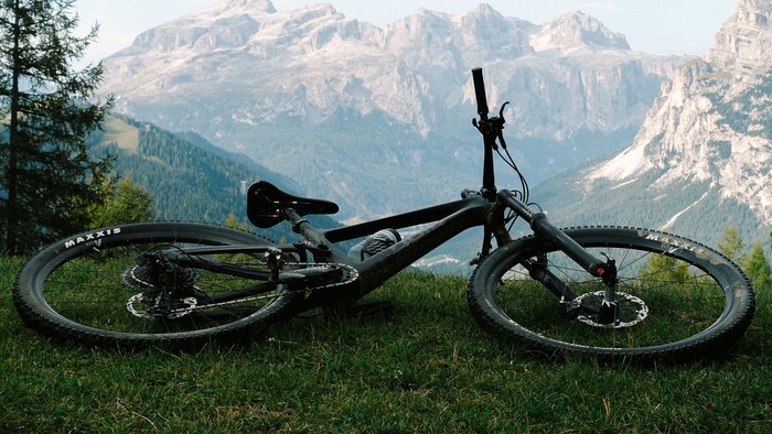Mountainbike liegt auf Gras mit Bergpanorama im Hintergrund