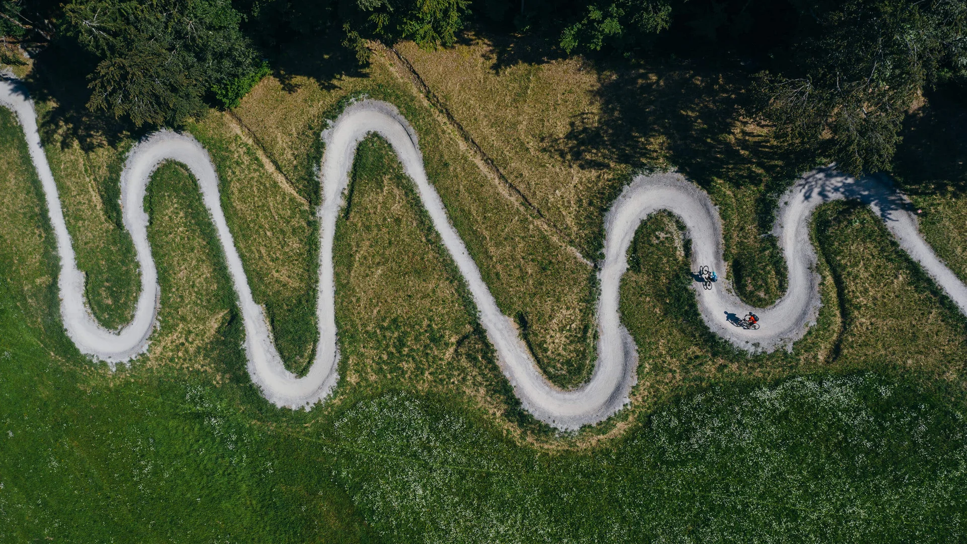 Luchtfoto van een kronkelend fietspad met twee fietsers in het groen
