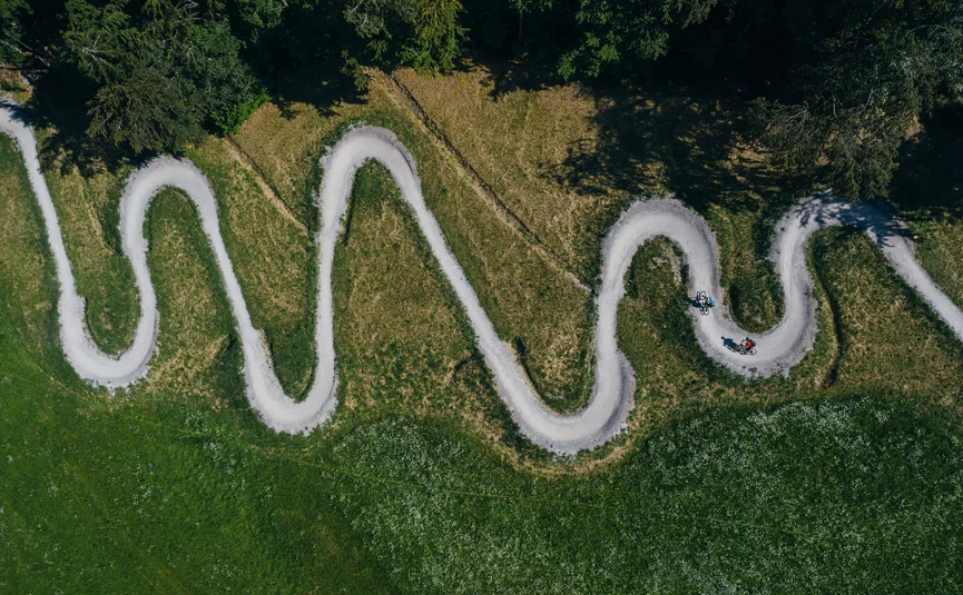 Luchtfoto van een kronkelend fietspad met twee fietsers in het groen