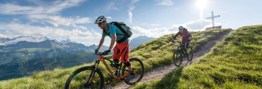 Two mountain bikers riding on a sunny mountain trail