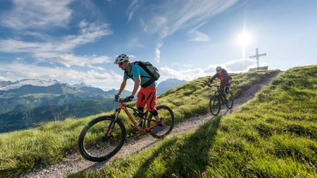 Zwei Mountainbiker fahren auf einem Bergpfad bei Sonnenschein