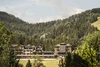 Hotelgebäude umgeben von Wäldern und Bergen unter bewölktem Himmel