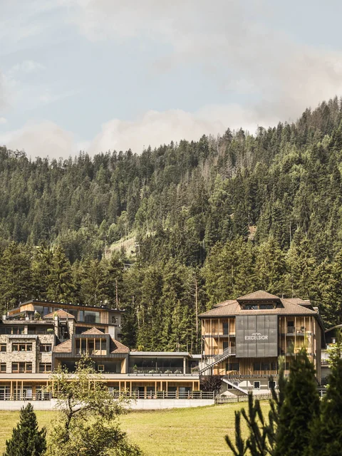 Hotelgebäude umgeben von Wäldern und Bergen unter bewölktem Himmel