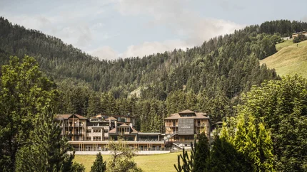 Hotelgebäude umgeben von Wäldern und Bergen unter bewölktem Himmel