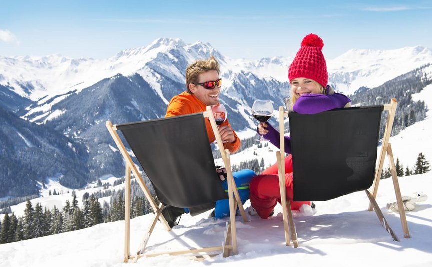 SKI+WINE - 3 nights Two people sitting on deck chairs in snow holding wine glasses