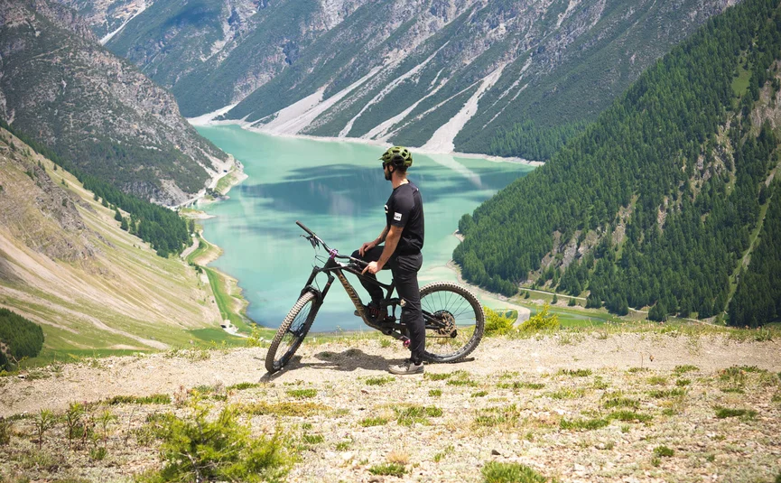 Radfahrer blickt auf Bergsee in alpiner Landschaft