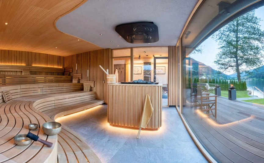 Moderne Sauna mit Holzbänken und Blick auf See und Berge