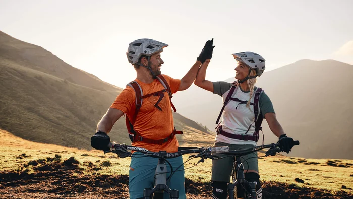 Happy Birthday EPIC Bike Park! © Tobias Köhler Zwei Mountainbiker geben sich beim Halten der Fahrräder Highfive im Gebirge
