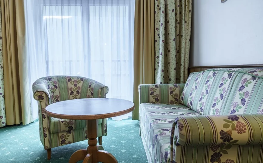 Seating area with floral upholstered furniture and small wooden table by window