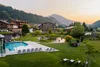 Bergresort mit Pool, Liegestühlen und grüner Landschaft im Sonnenuntergang
