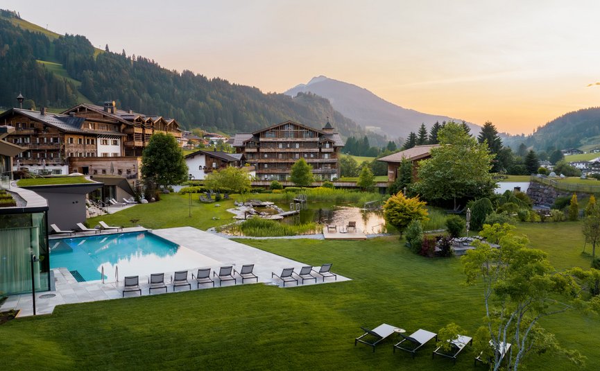 Puradies © creatingclick Bergresort mit Pool, Liegestühlen und grüner Landschaft im Sonnenuntergang