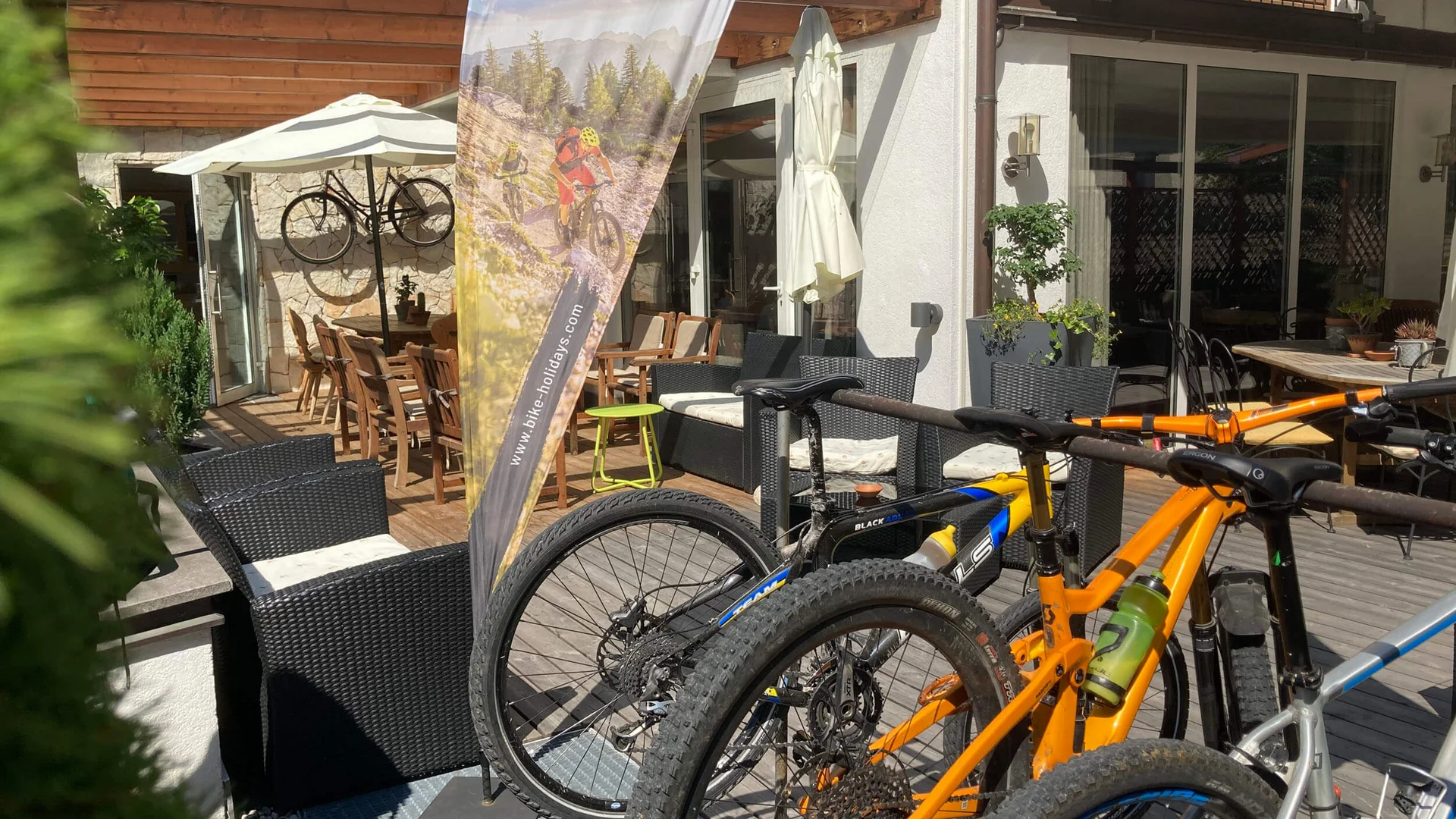 Auf Trail-Mission im Ahrntal © Hotel Innerhofer Mountainbikes vor Lodge mit Mountain Bike Holidays Fahne