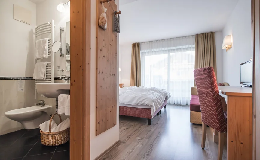 Modern hotel room with bathroom, bed, desk, and balcony