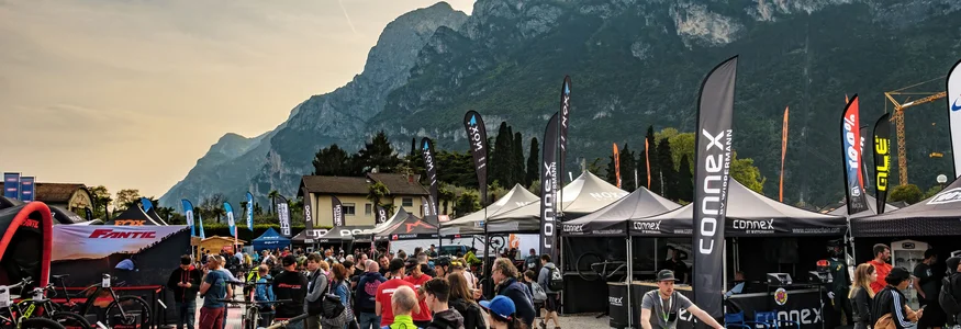 Mountainbike-Event-Highlights
© APTGardaDolomitiSpA ph Castagna BIKEFESTIVAL - EVENT ExpoArea Menschen auf einer Fahrradmesse mit Bergen im Hintergrund