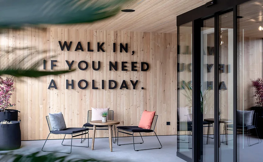 Seating area with chairs, table, and sign Walk in, if you need a holiday