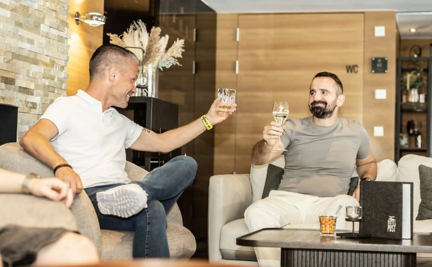 Two men sitting and toasting drinks in a cozy lounge