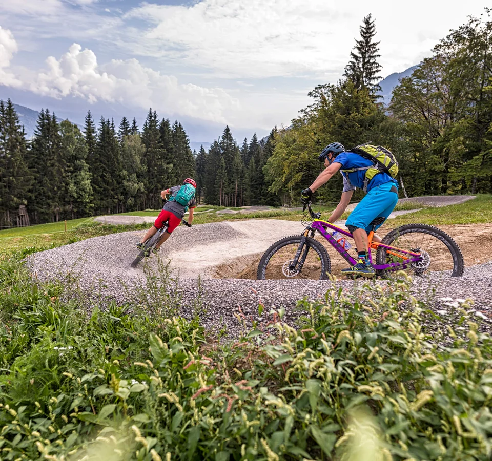 Zwei Radfahrer fahren auf einem geschwungenen Mountainbike-Trail im Wald