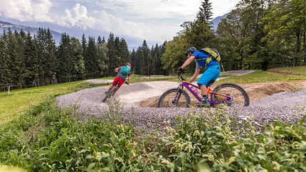 Zwei Radfahrer fahren auf einem geschwungenen Mountainbike-Trail im Wald