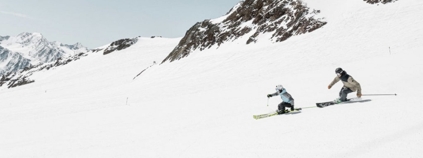 Two skiers skiing down a snowy mountain slope
