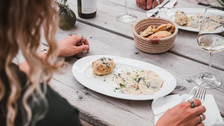 Mountainbiken im Herbst: 5 Top-Regionen für die Saisonverlängerung © Brixen Tourismus - Hannes Engl Person isst Nudeln und Knödel mit Wein auf Holztisch