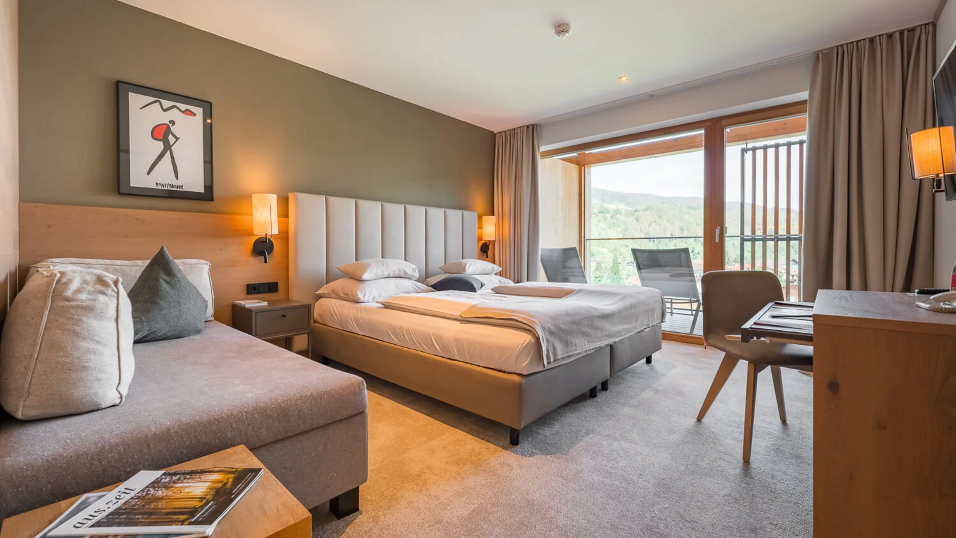 Moderne Hotelzimmer mit Doppelbett, Sofa und Balkon mit Bergblick