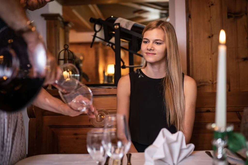 Kulinarische Nächte / 2 Nächte Vrouw zit aan tafel, ober schenkt wijn in glas