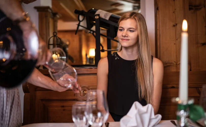 Kulinarische Nächte / 2 Nächte Vrouw zit aan tafel, ober schenkt wijn in glas