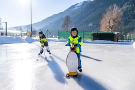 Family Ski & Ice Weeks Two children ice skating outdoors on a mountain rink
