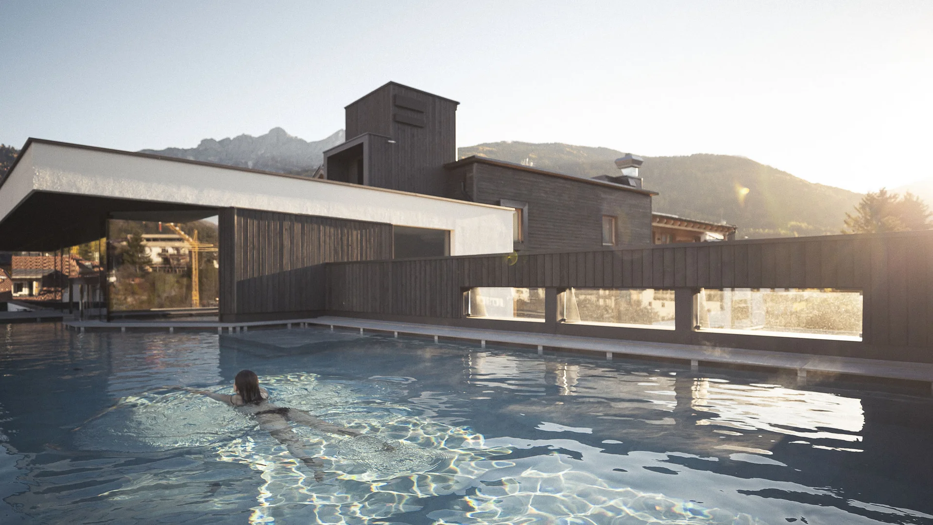 BEST OF Familien-Bikeurlaub © Kottersteger Person schwimmt in einem Außenpool mit moderner Architektur im Hintergrund