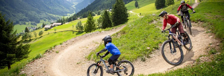 Brandnertal © Michael Marte - Bikepark Brandnertal Three mountain bikers riding on a mountain trail in the Alps
