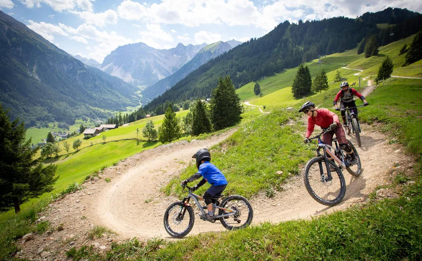 Drie mountainbikers op een bergpad in de Alpen