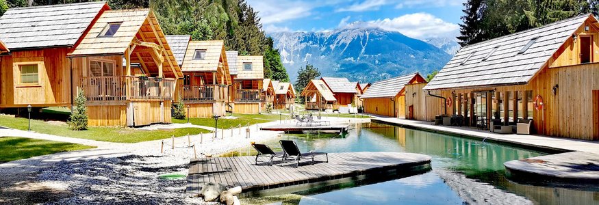 Holzhütten am See mit Bergblick und zwei Liegestühlen am Steg