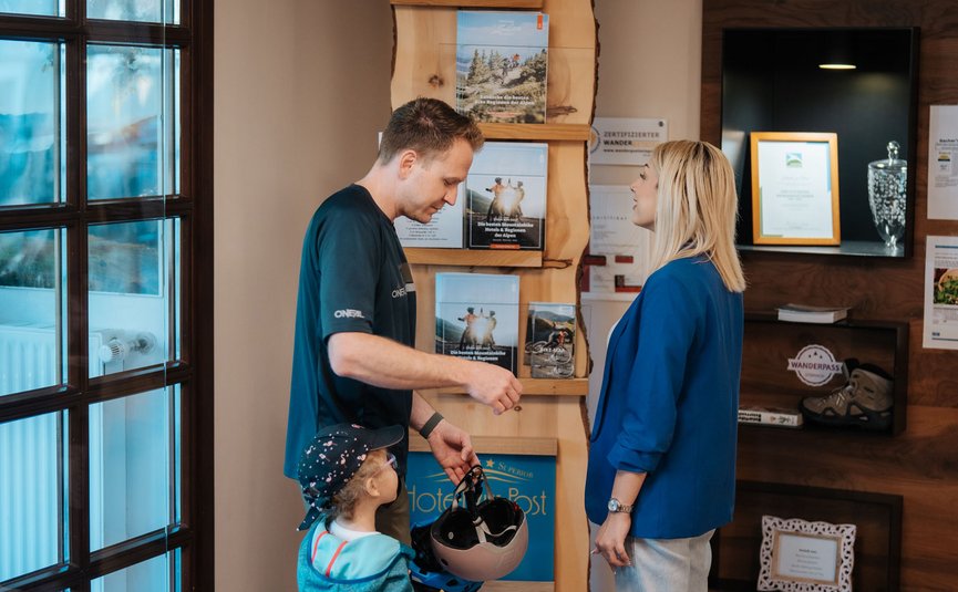 Man en vrouw met kind bij de receptie van een hotel