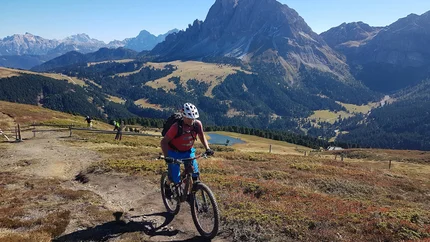 Mountain biker riding on a trail with mountain scenery in the background