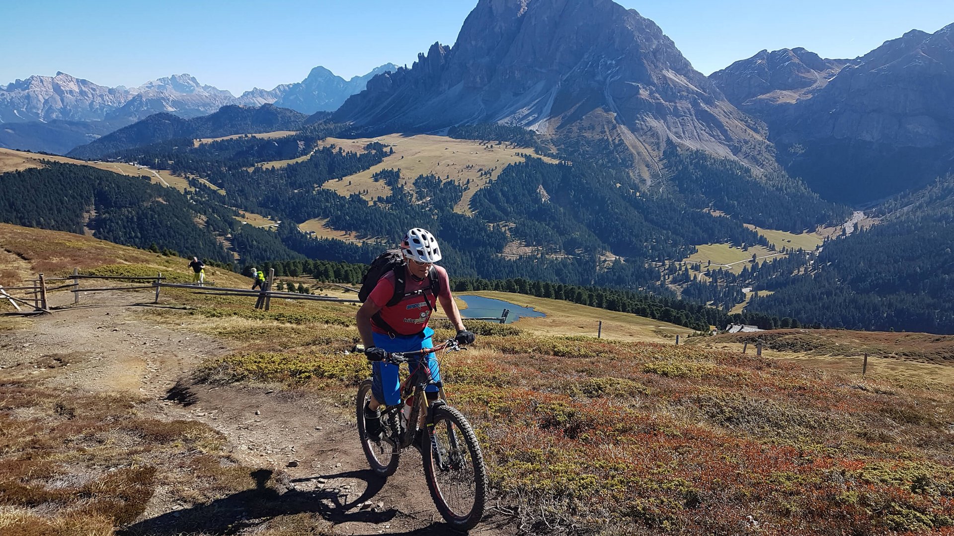 Mountainbiker fährt auf einem Pfad mit Bergpanorama im Hintergrund