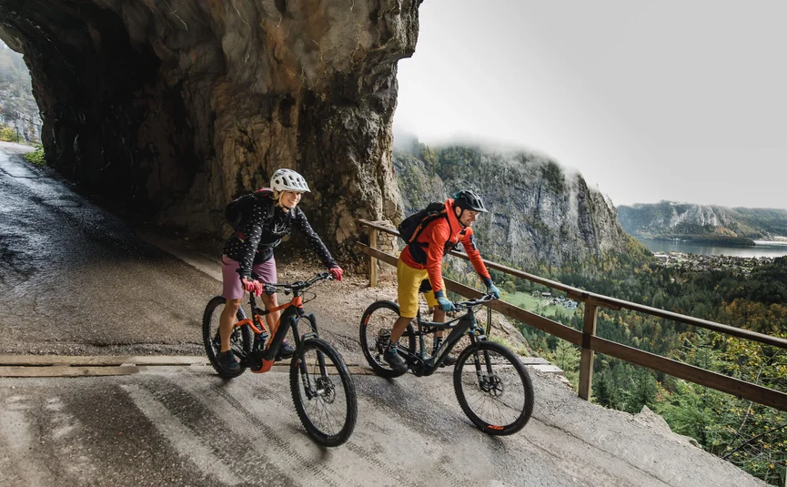 Twee mountainbikers op bergpad met tunnel en uitzicht op dal