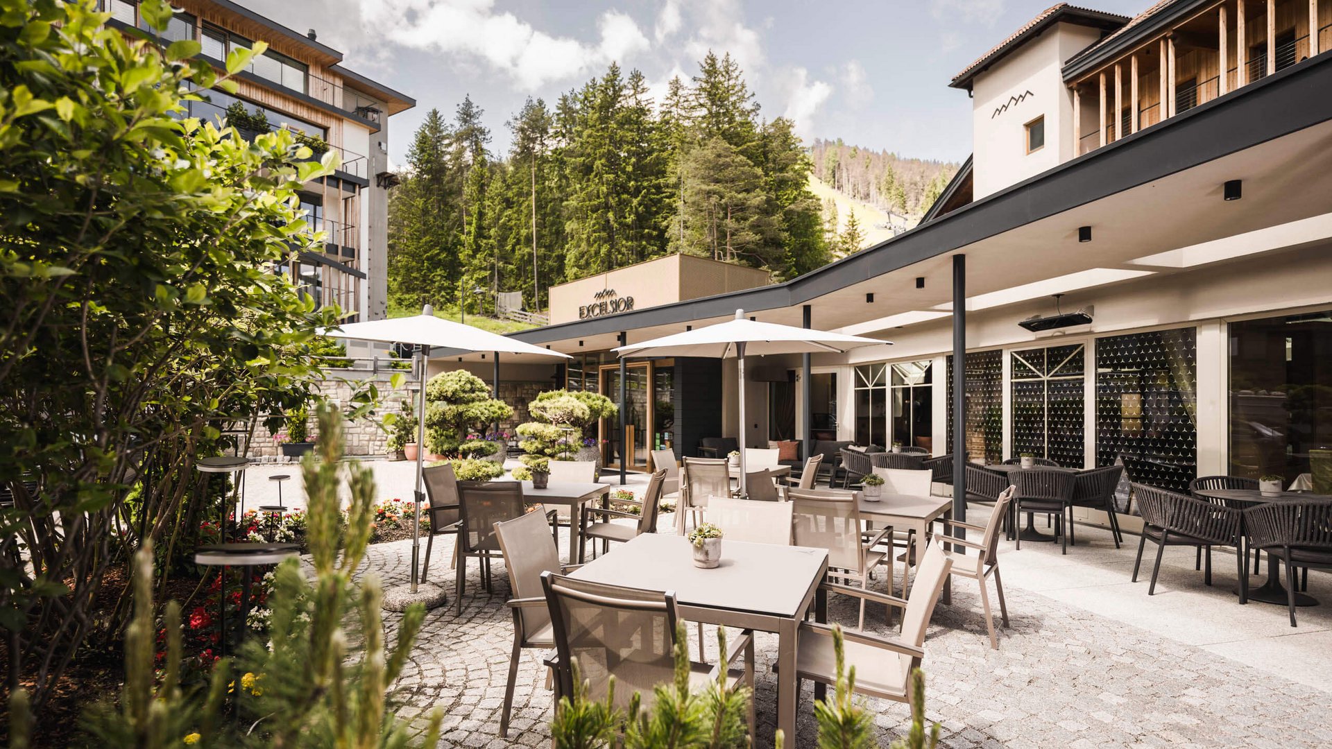 Mountainbike-Saisonstart am Kronplatz © Hannes Niederkofler Außenterrasse mit Tischen, Stühlen und Sonnenschirmen vor Hotel Excelsior