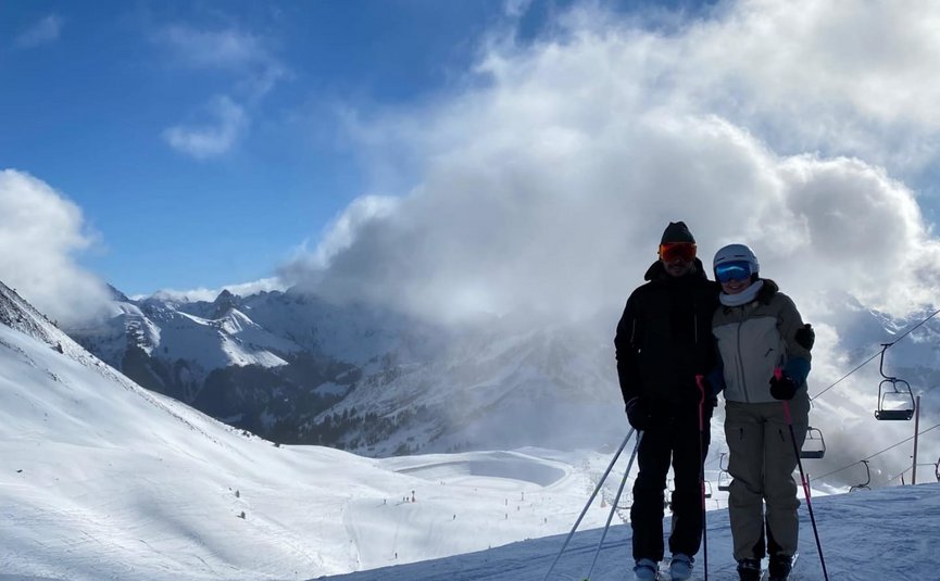 Two skiers on a snowy mountain under blue sky with clouds