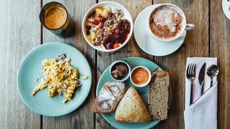 Best of Brandnertal © Manuel Dietrich Frühstück mit Rührei, Brot, Müsli, Kaffee und Orangensaft auf Holztisch