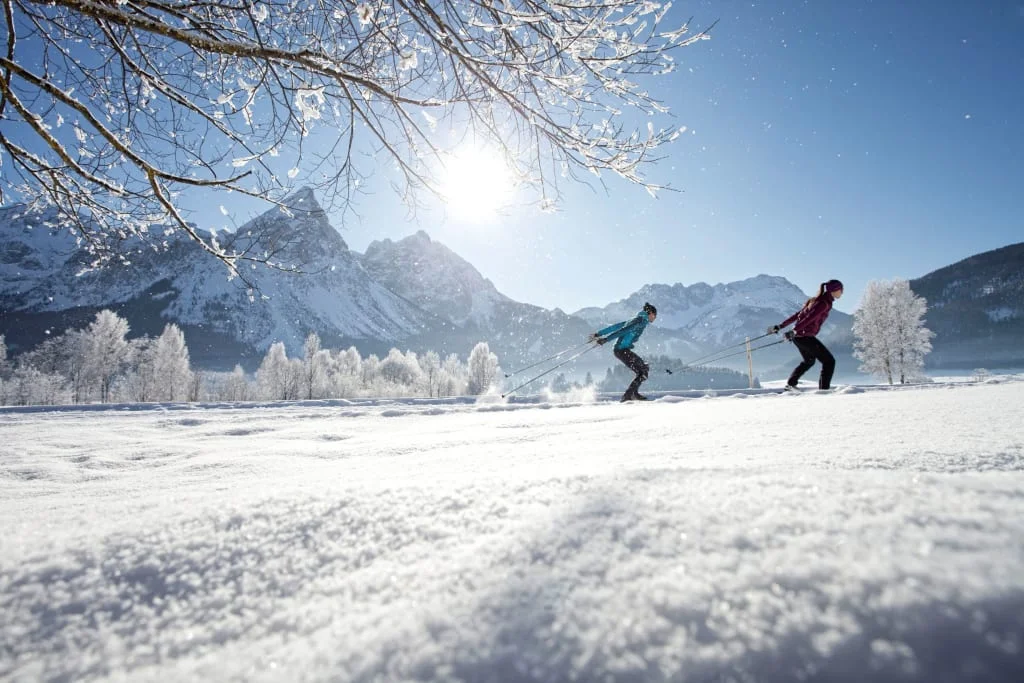 Langlauf Short Stay 4 Tage 2026-27 Zwei Personen beim Langlaufen in sonniger, verschneiter Berglandschaft