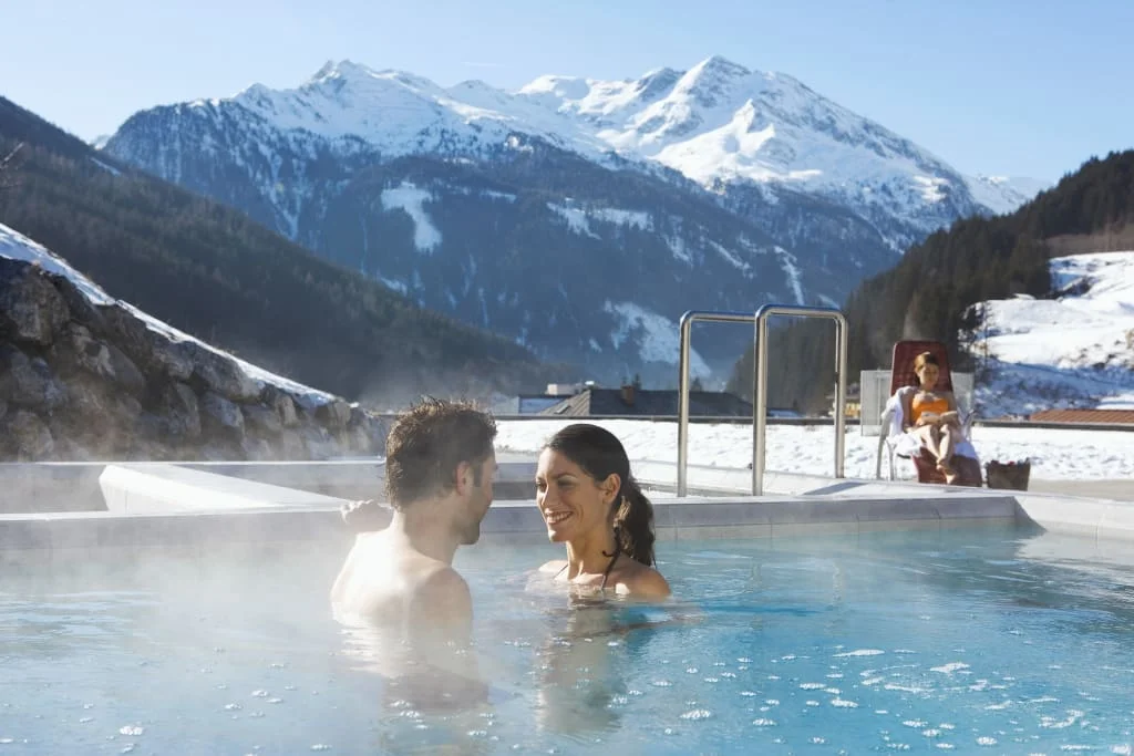 Paar im beheizten Pool mit schneebedeckten Bergen im Hintergrund