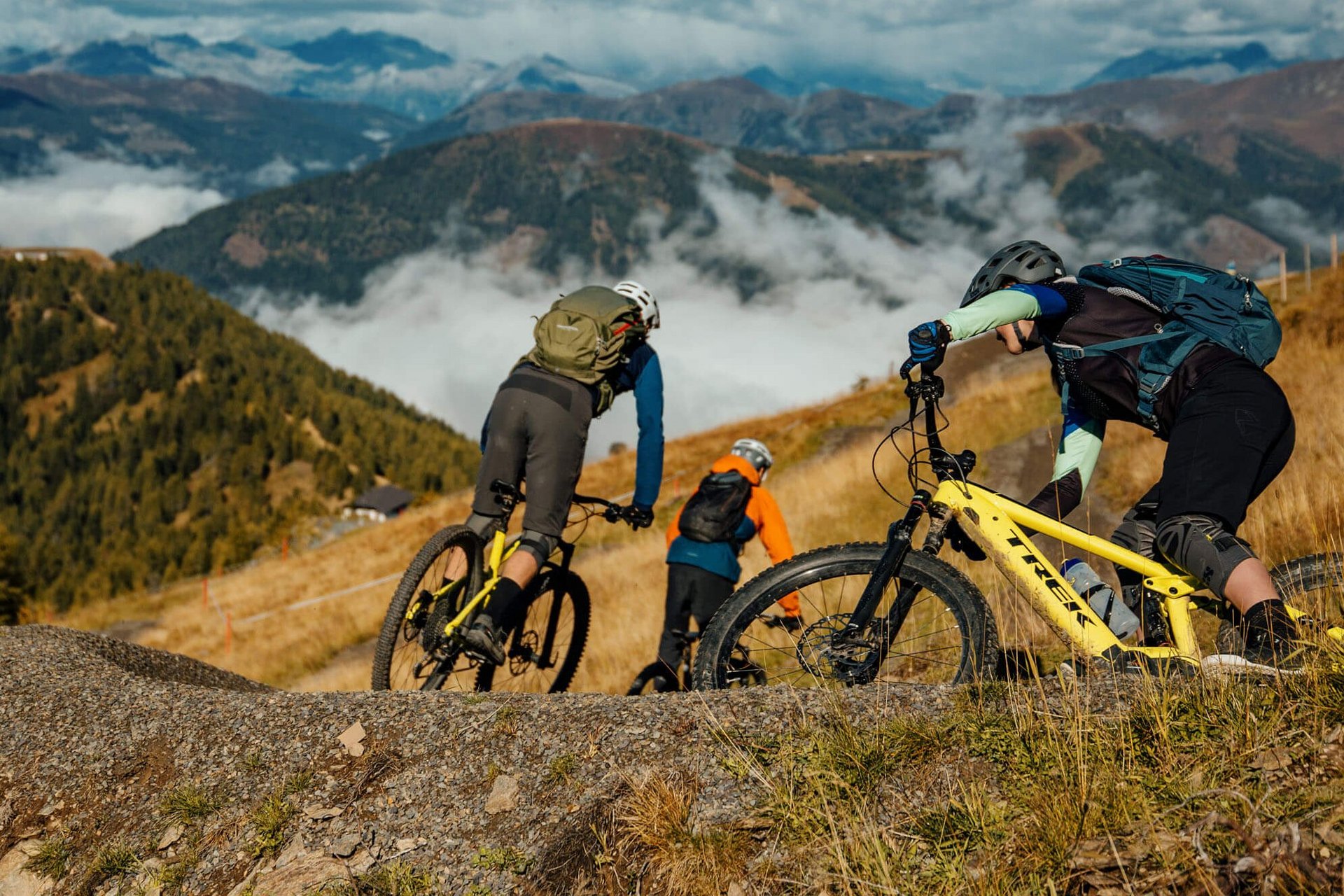 Drei Mountainbiker fahren auf einem Pfad in den Bergen bei klarem Himmel