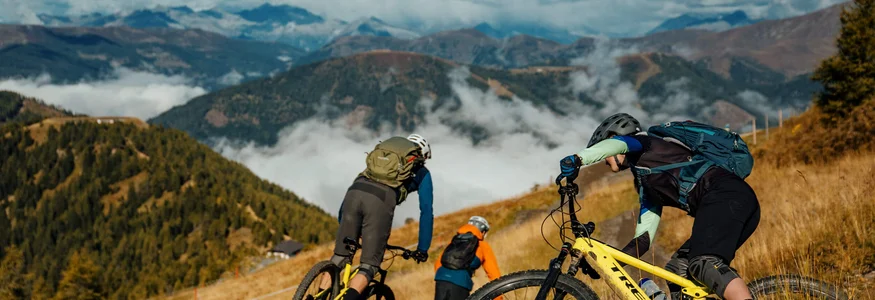 Die besten Touren & Trails der Alpen © David Karg Drei Mountainbiker fahren auf einem Pfad in den Bergen bei klarem Himmel