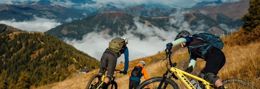 Mountainbiken im Herbst: 5 Top-Regionen für die Saisonverlängerung © David Karg Drei Mountainbiker fahren auf einem Pfad in den Bergen bei klarem Himmel